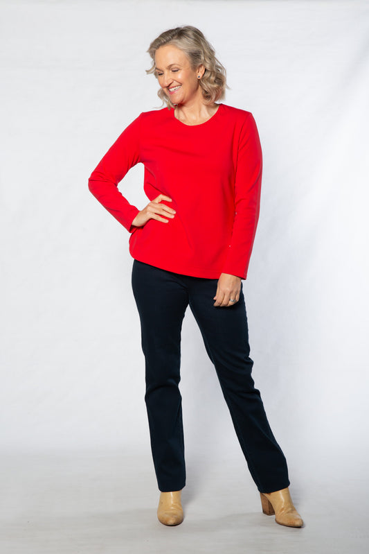 Woman wearing a red sweater and black pants against a white background