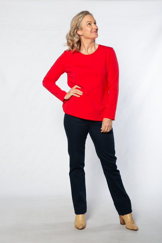 Woman wearing a red sweater and black pants against a white background