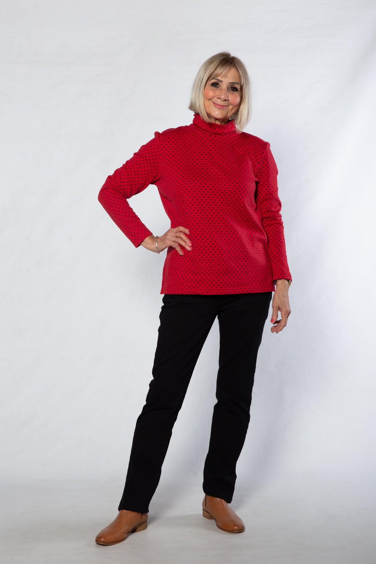 Woman wearing a red sweater and black pants on a white background