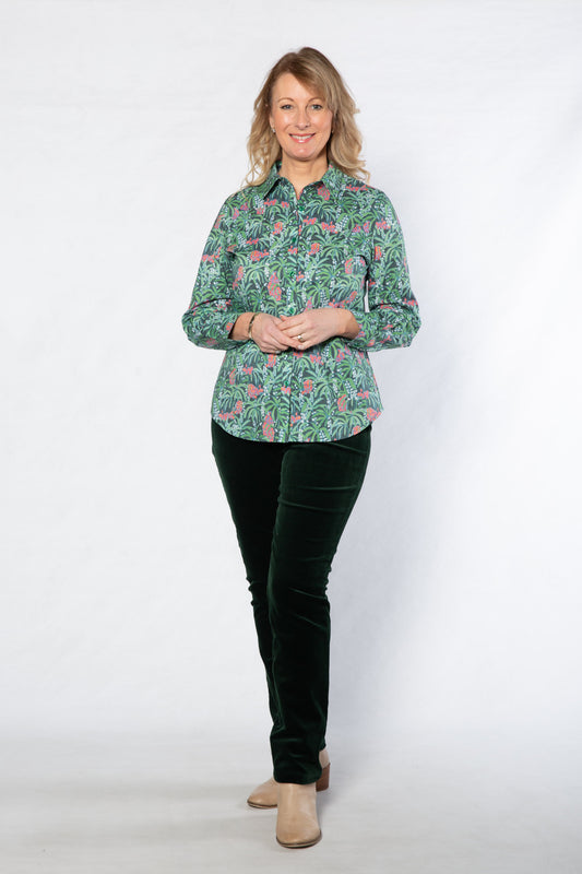 Woman wearing a green floral blouse and black pants on a white background
