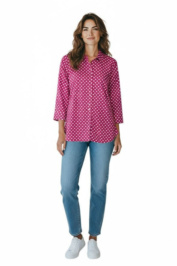 Woman wearing a pink polka dot blouse and blue jeans on a white background