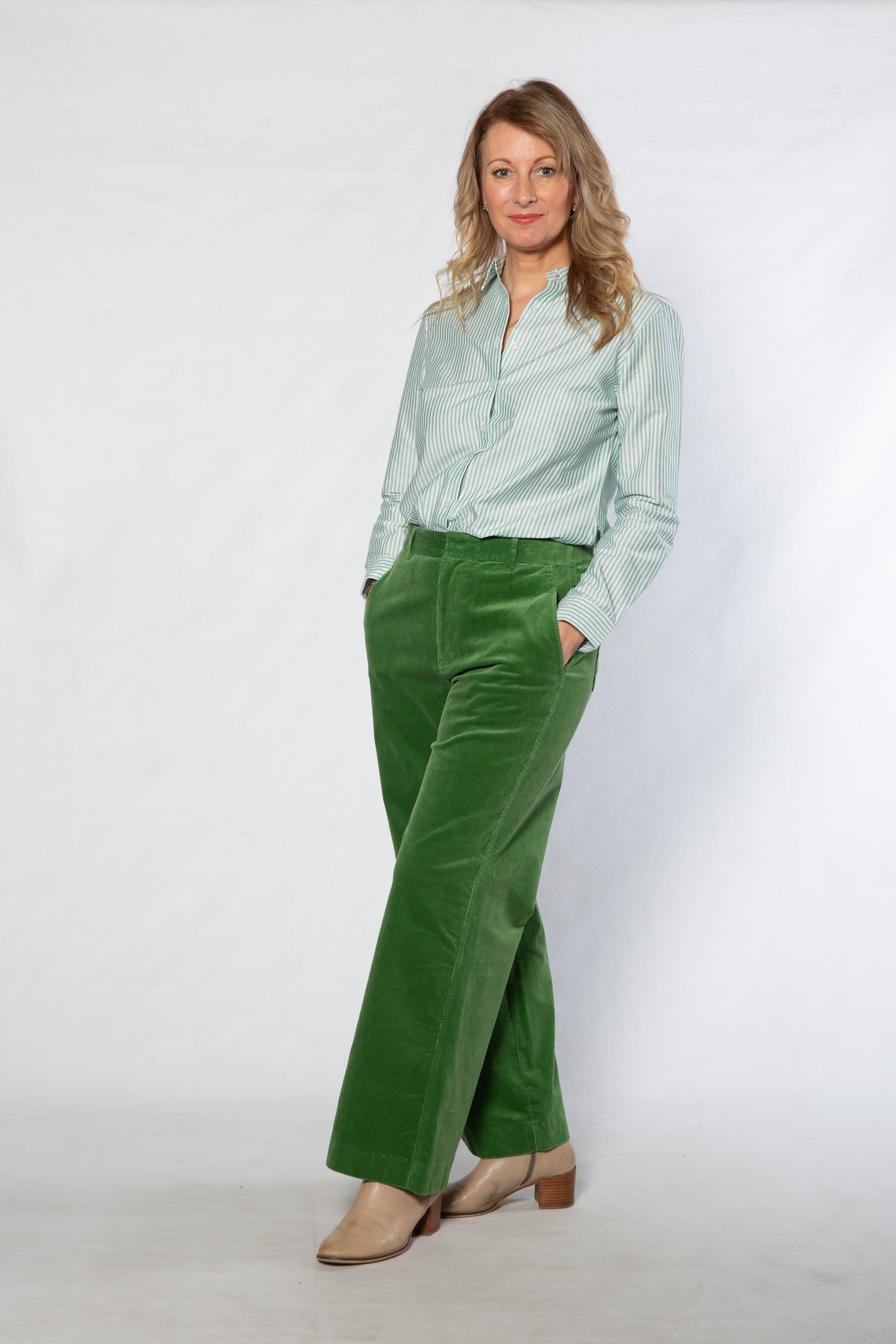 Woman wearing a light green shirt and green pants against a white background
