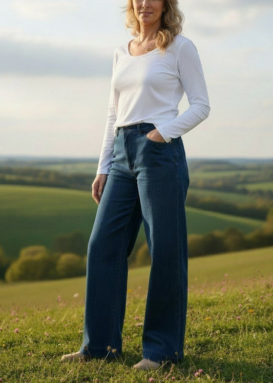 Woman standing in a field with green hills and trees in the background