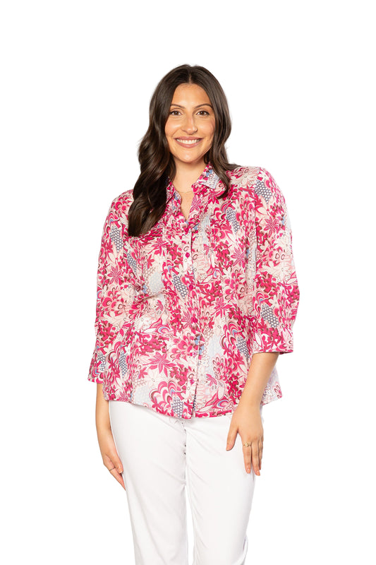 Woman wearing a pink floral blouse and white pants on a white background