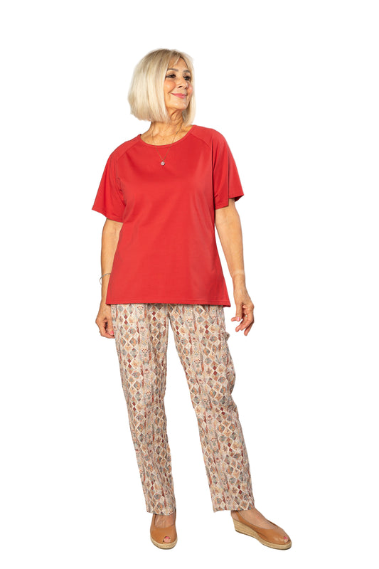 Woman wearing a red top and patterned pants on a white background