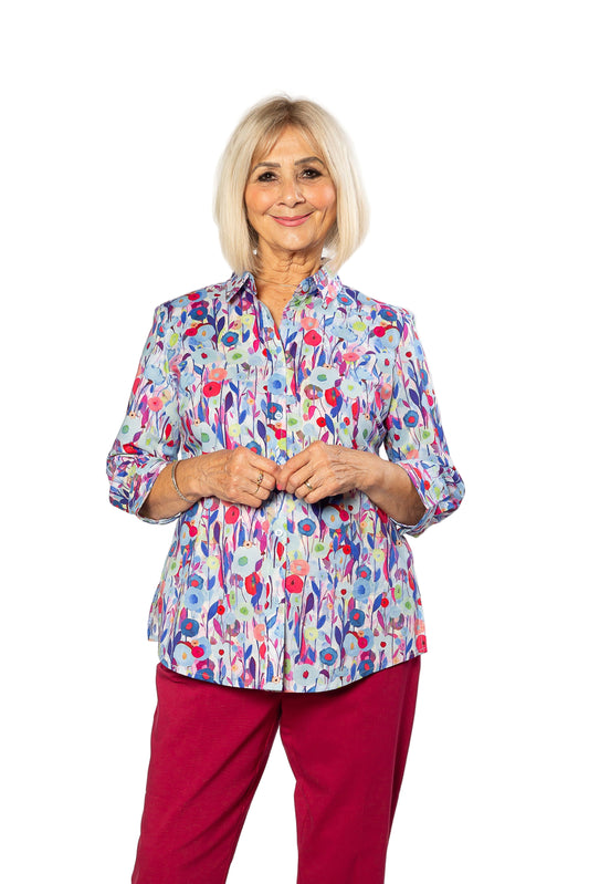Woman wearing a colorful floral blouse and red pants on a white background