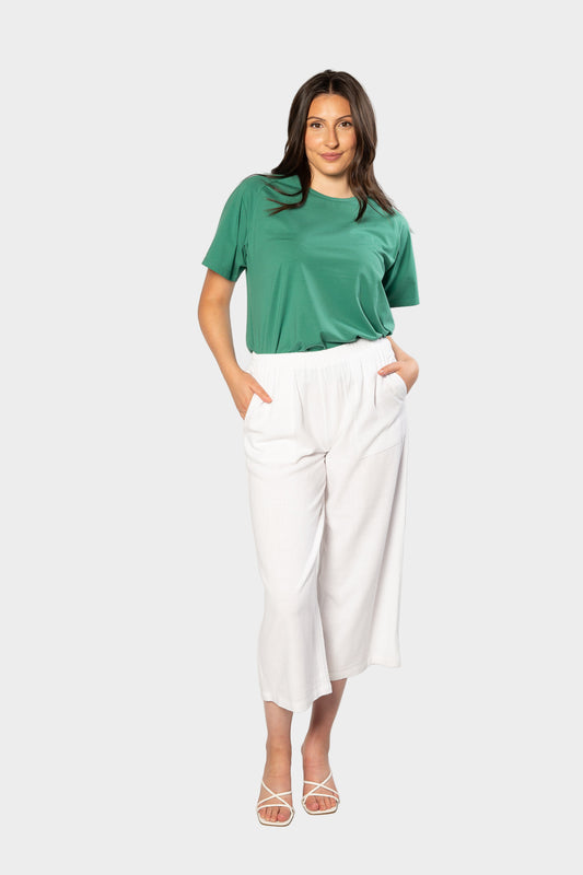 Woman wearing a green t-shirt and white pants on a white background