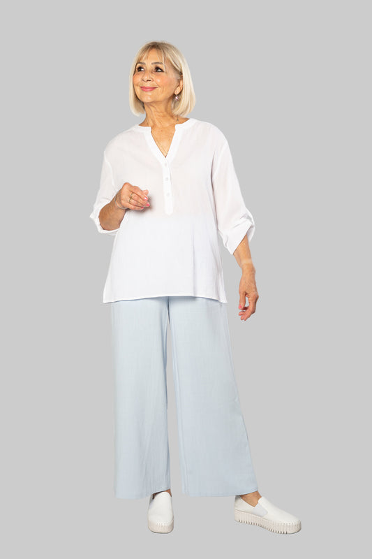 Woman wearing a white shirt and light blue pants against a white background