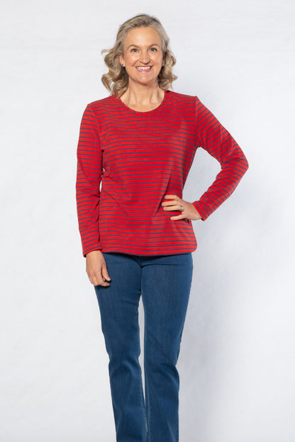 Woman wearing a red striped top and blue jeans standing against a white background