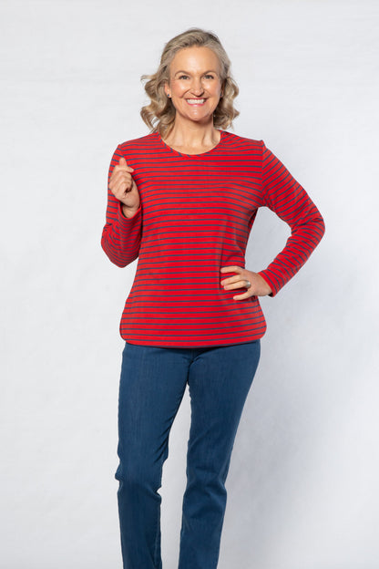 Woman wearing a red striped sweater and blue jeans standing against a white background