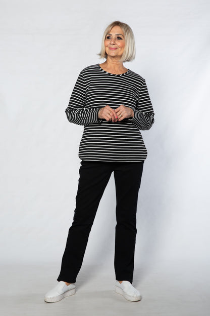 Person wearing a black and white striped sweater and black pants on a white background