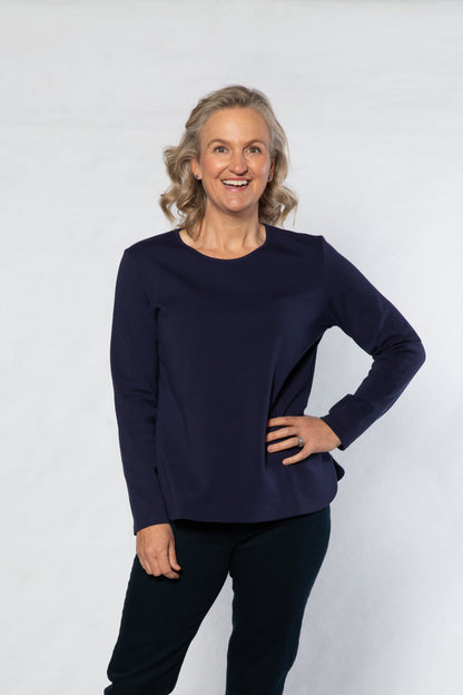 Woman wearing a navy sweater and black pants on a white background