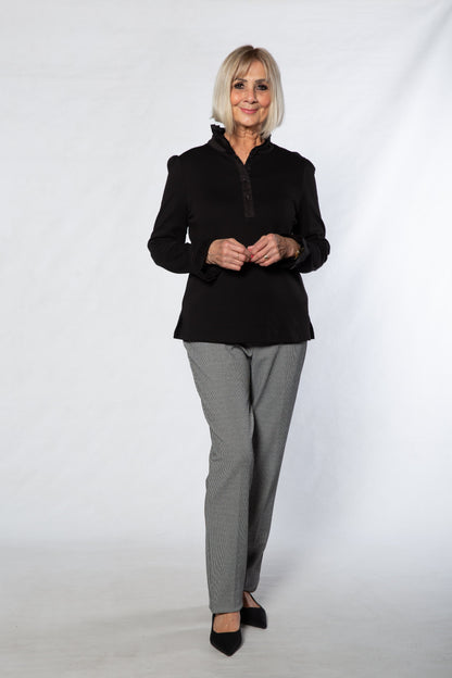 Woman wearing a black jacket and gray pants against a white background