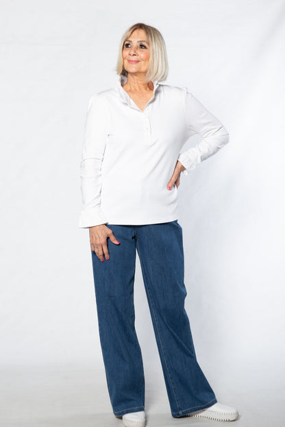 Woman wearing a white shirt and blue jeans standing against a white background