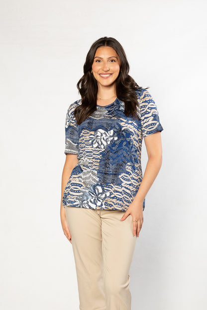 Woman wearing a blue patterned top and beige pants on a white background