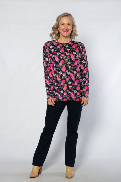 Woman wearing a floral patterned top and black pants on a white background