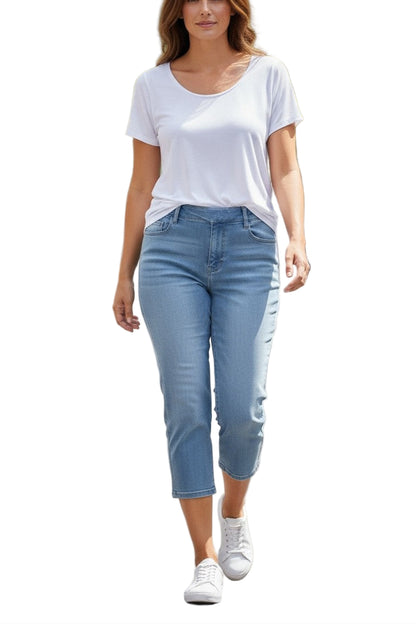 Woman walking on a street wearing a white t-shirt and light blue jeans.