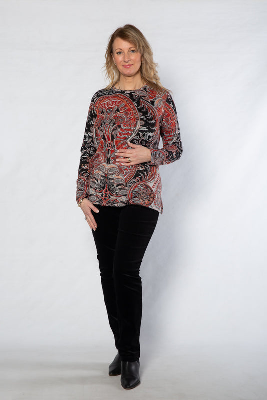 Woman wearing a patterned top and black pants on a white background