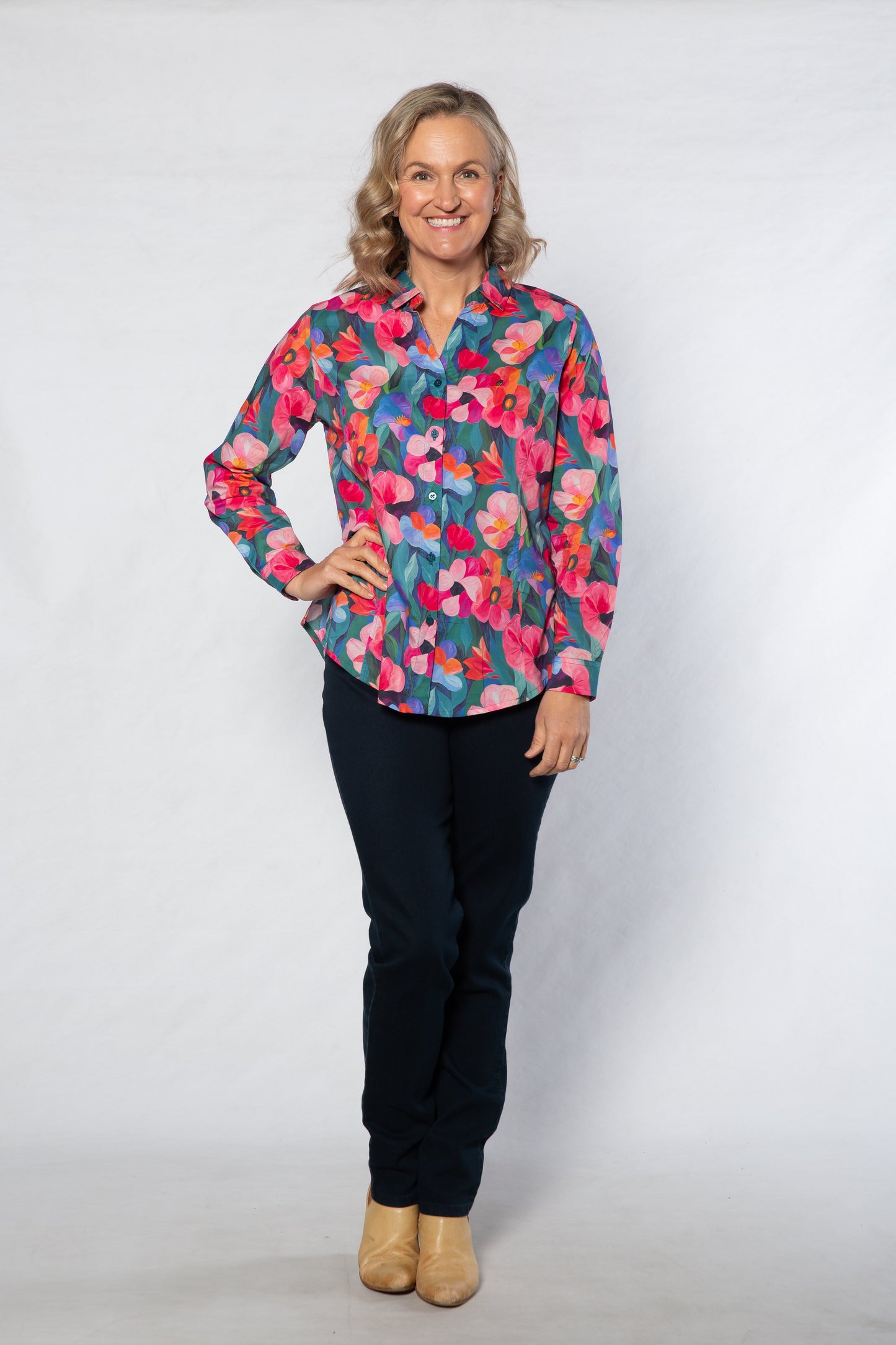 Woman wearing a colorful floral blouse and black pants on a white background