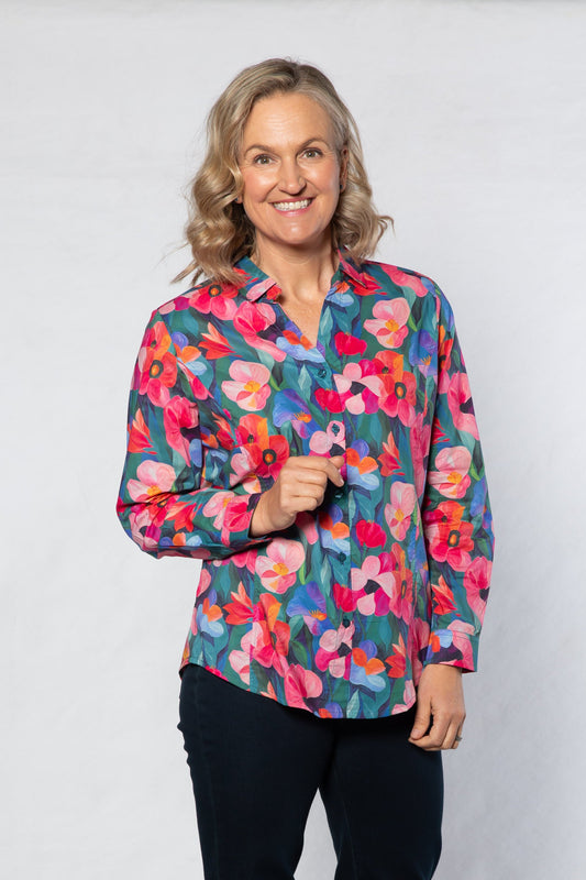 Woman wearing a colorful floral blouse and black pants on a white background