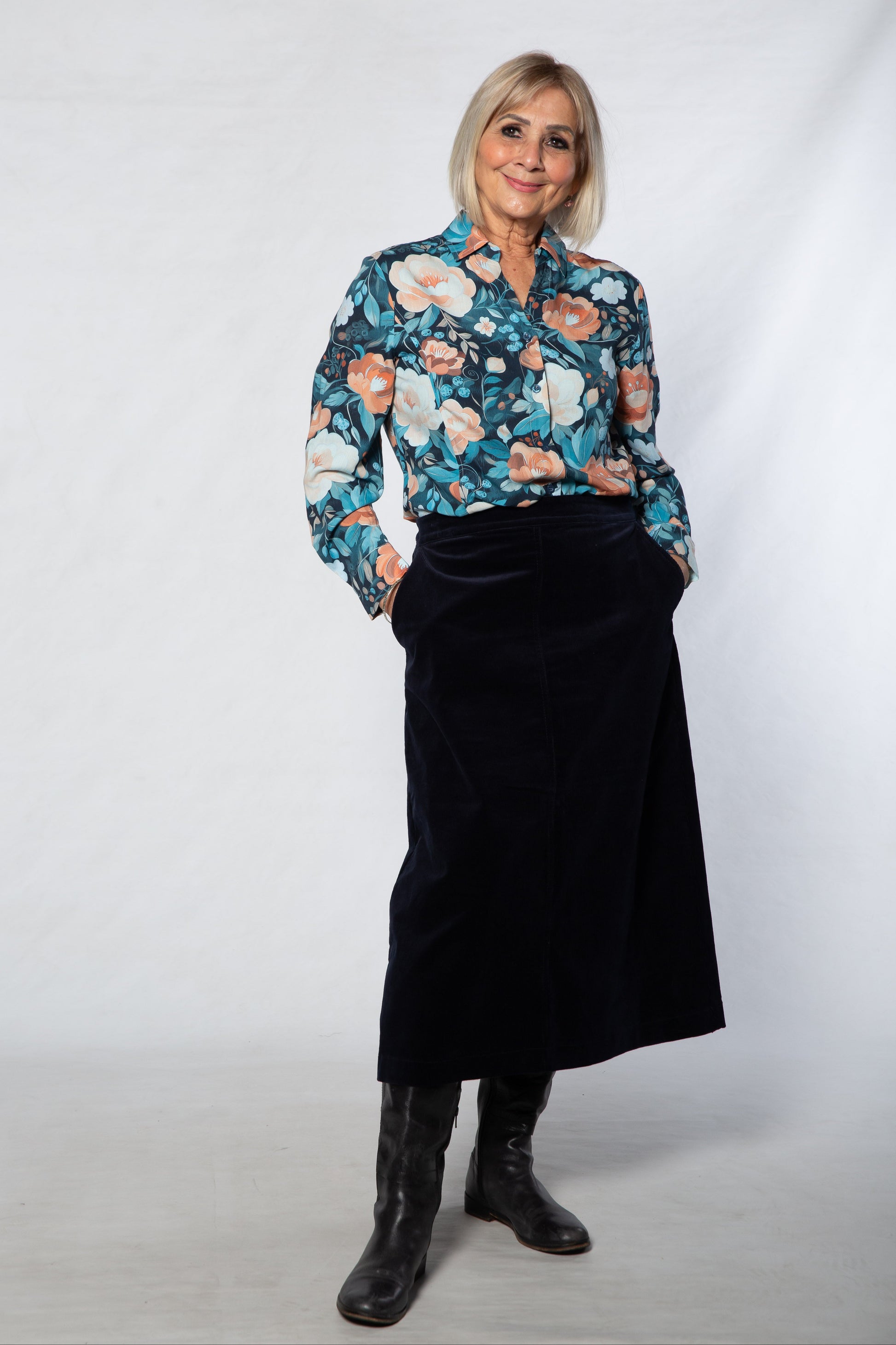 Woman wearing a floral blouse and black skirt against a white background