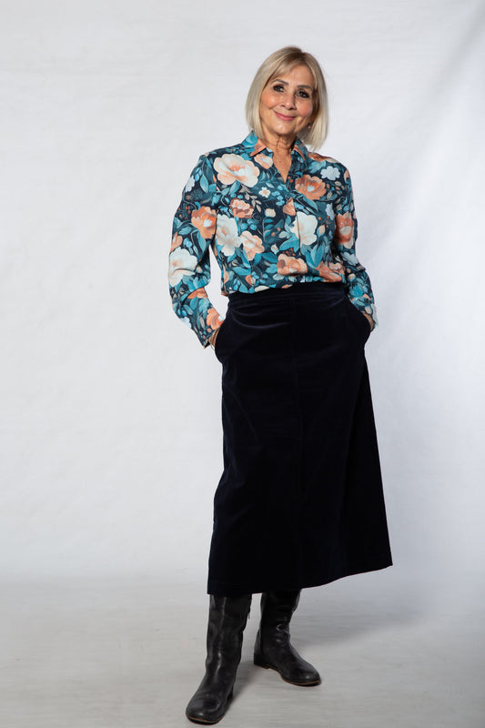 Woman wearing a floral blouse and black skirt against a white background