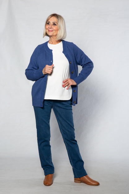 Woman wearing a blue cardigan, white shirt, and blue pants on a white background