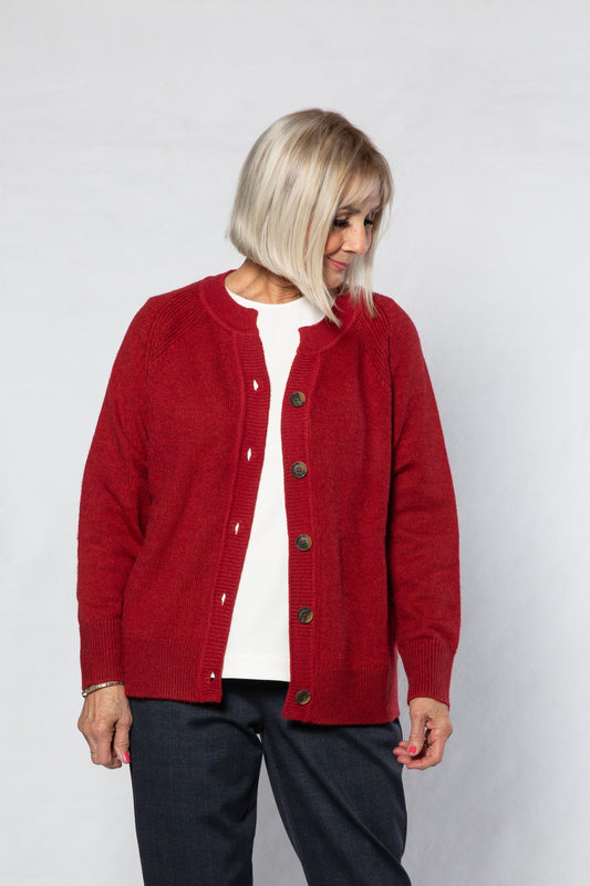 Person wearing a red cardigan over a white shirt with black pants on a white background