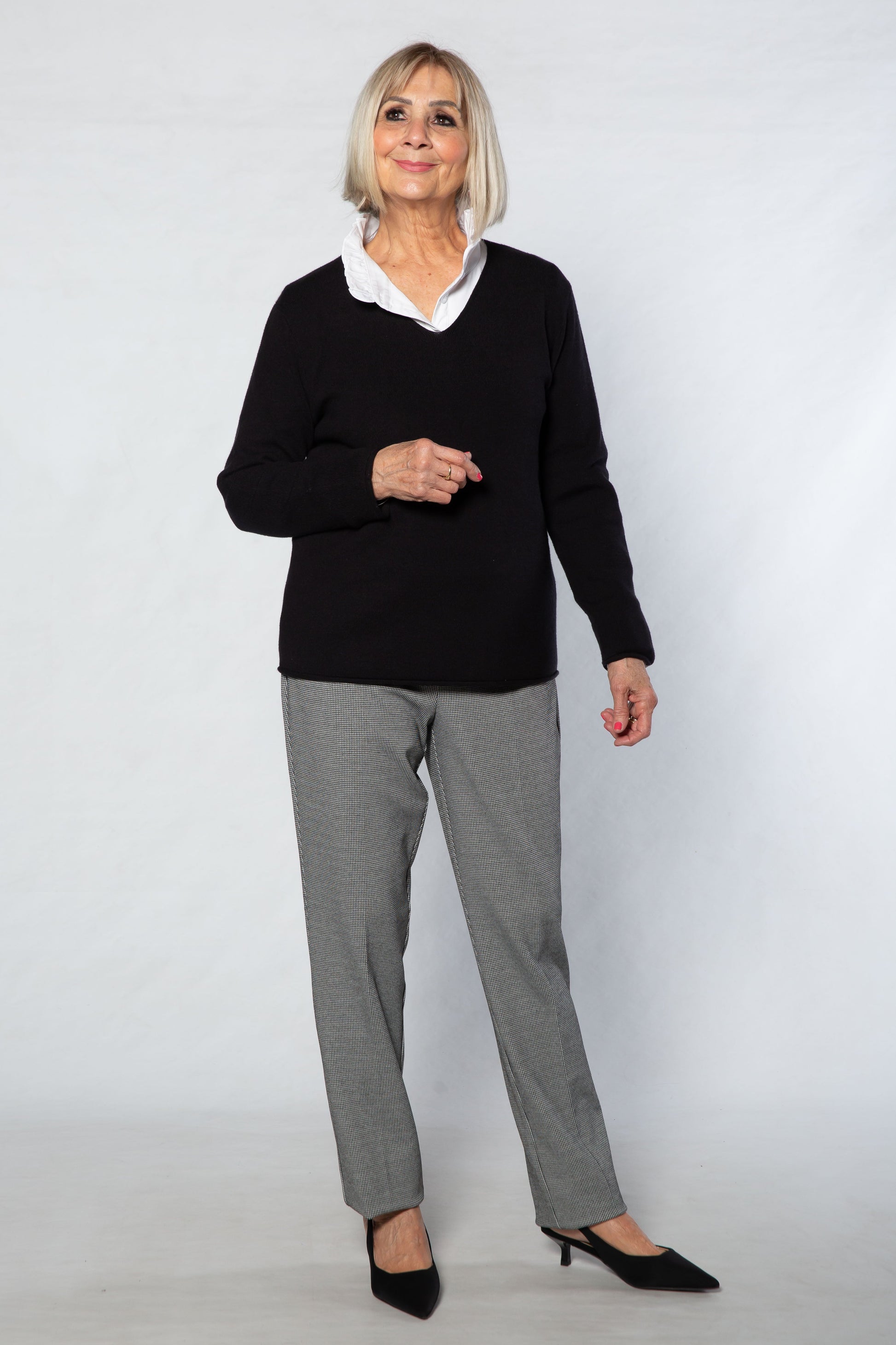 Woman wearing a black sweater and gray pants on a white background