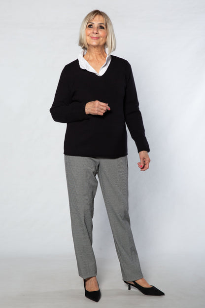 Woman wearing a black sweater and gray pants on a white background