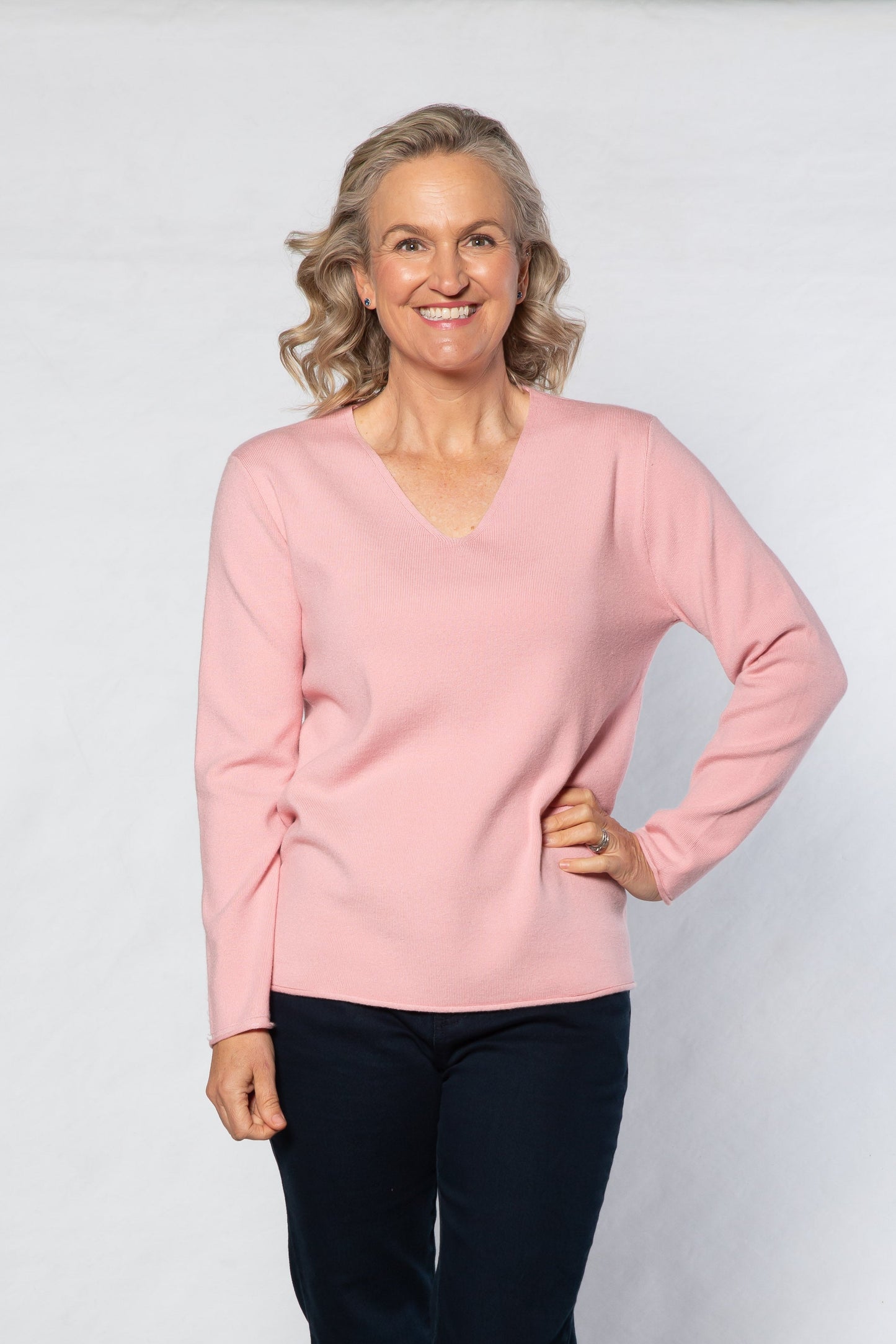 Woman wearing a pink sweater and black pants on a white background