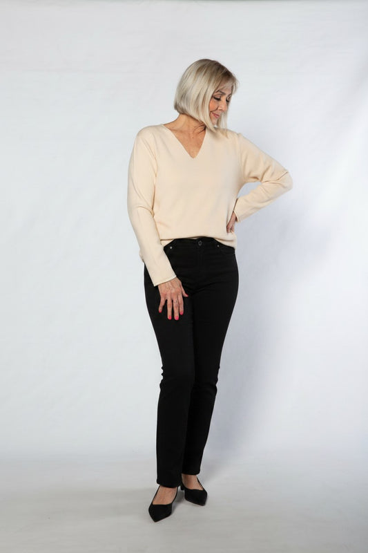 Woman wearing a beige sweater and black pants on a white background