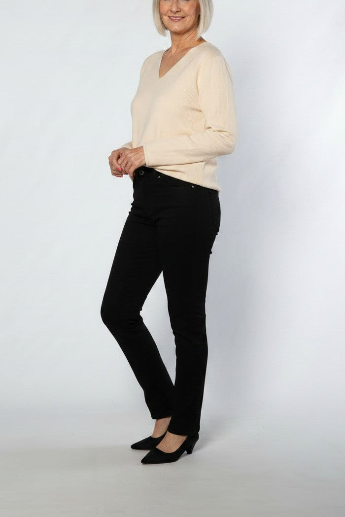 Woman wearing a beige sweater and black pants on a white background