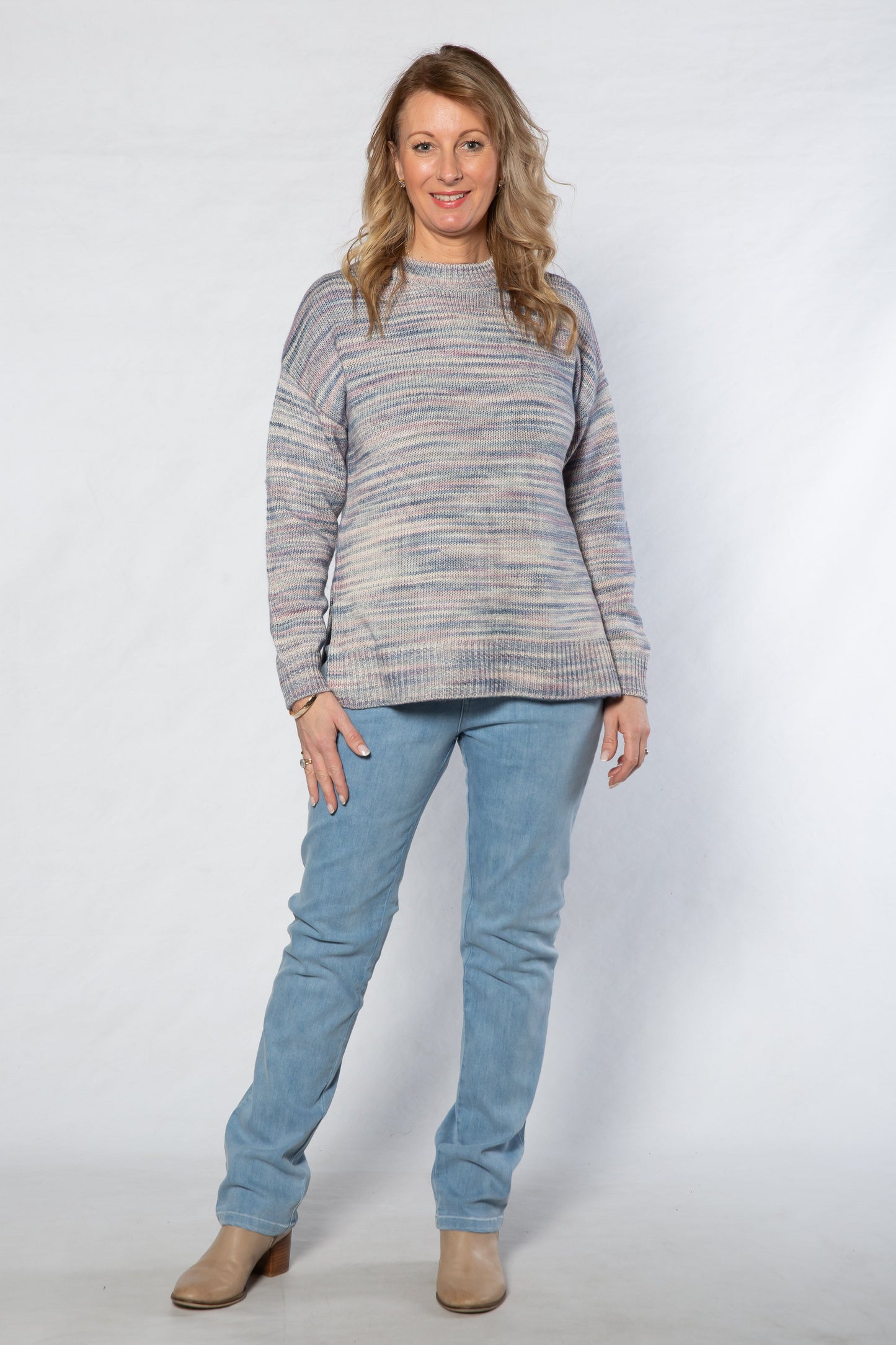 Woman wearing a striped sweater and blue jeans on a white background