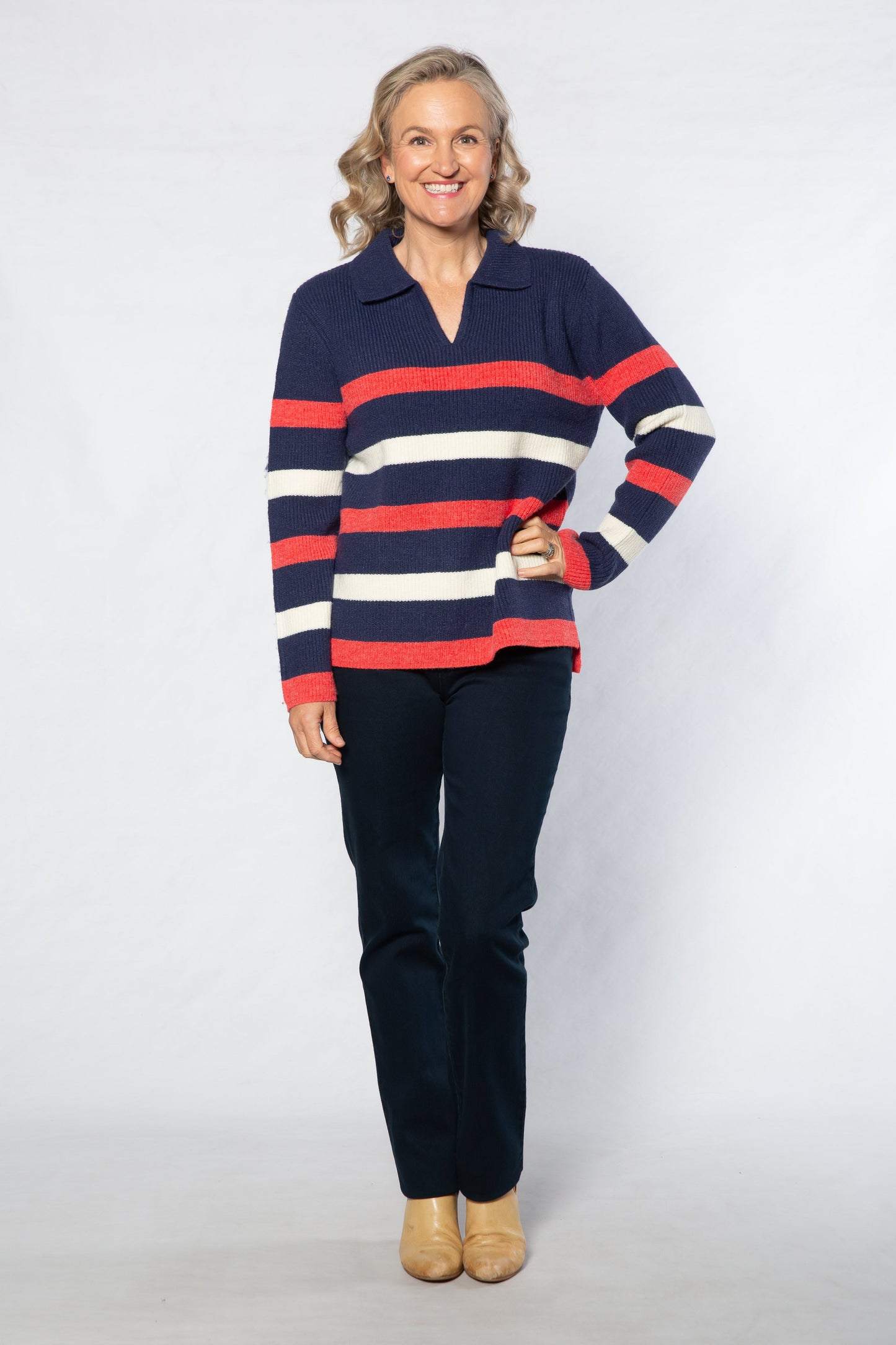 Woman wearing a striped sweater and dark pants on a white background