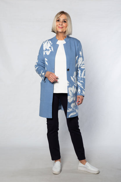 Person wearing a blue floral coat over a white shirt and black pants on a white background