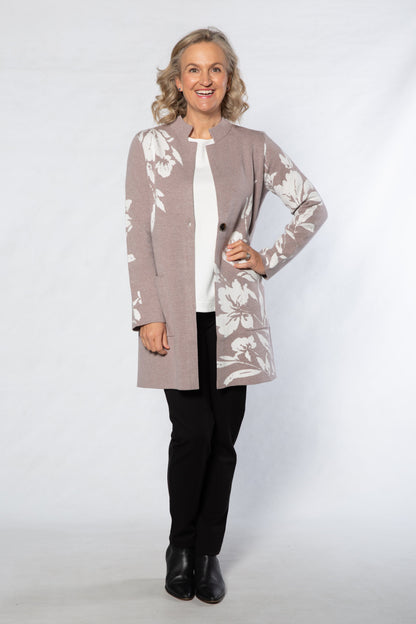 Woman wearing a patterned cardigan over a white shirt with black pants on a white background
