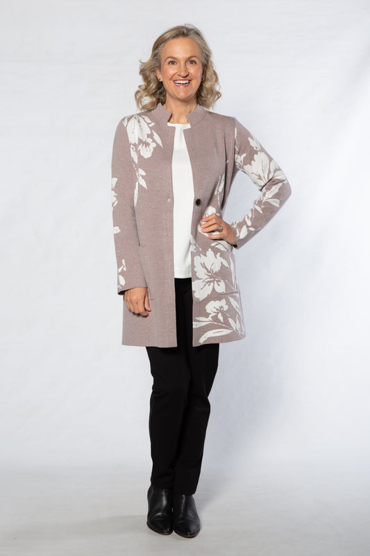 Woman wearing a patterned cardigan over a white shirt with black pants on a white background