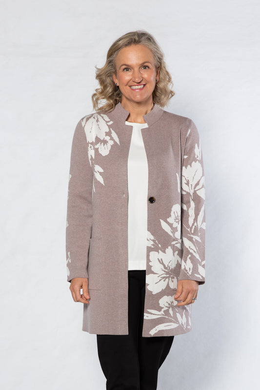 Woman wearing a long beige cardigan with floral pattern on a white background