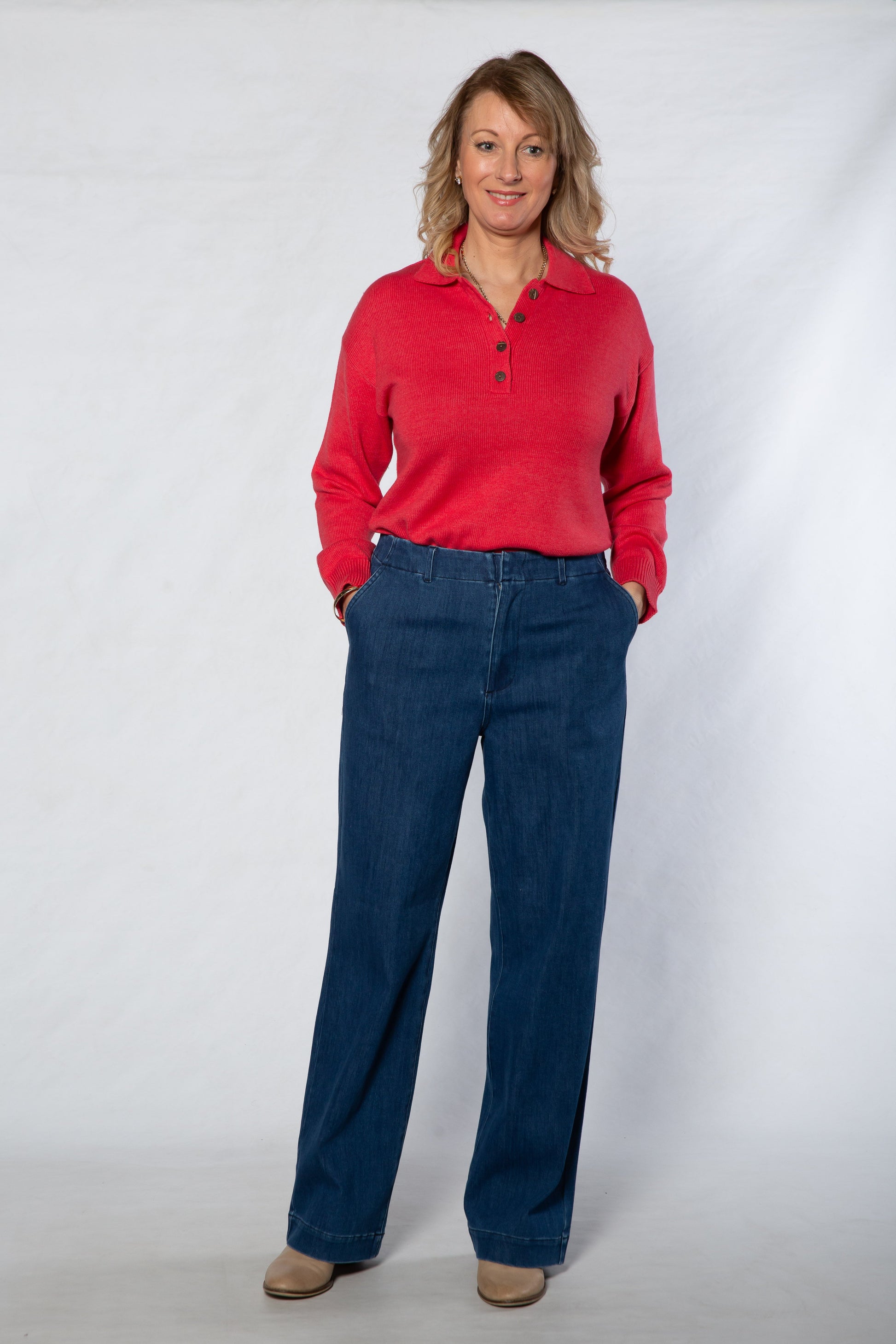 Woman wearing a red shirt and blue jeans against a white background