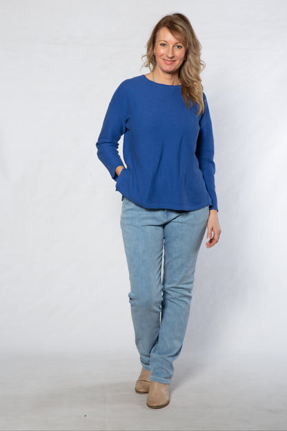 Woman wearing a blue top and light blue jeans against a white background