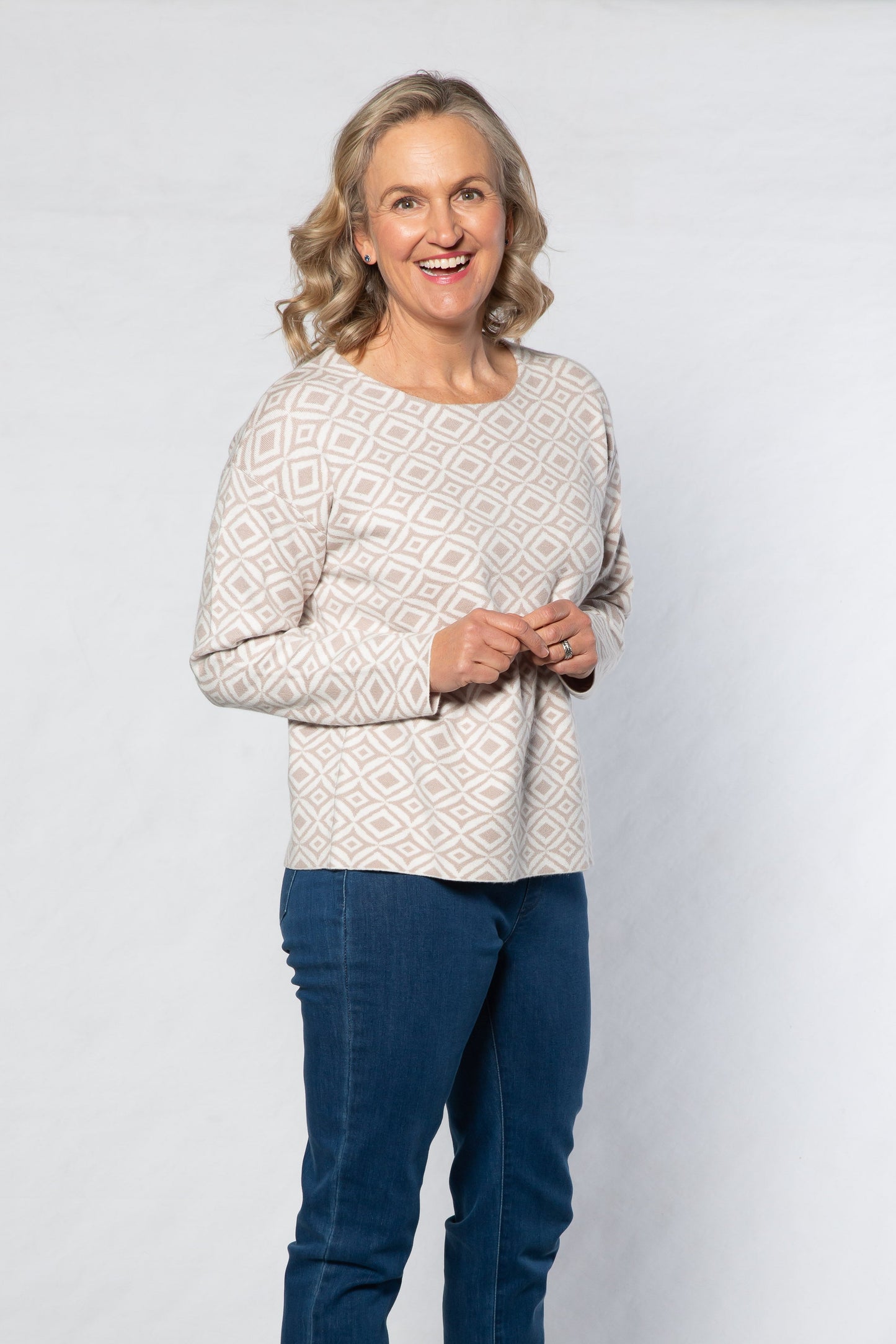Woman wearing a white sweater and blue jeans against a white background