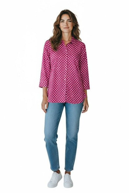 Woman wearing a pink polka dot blouse and blue jeans on a white background