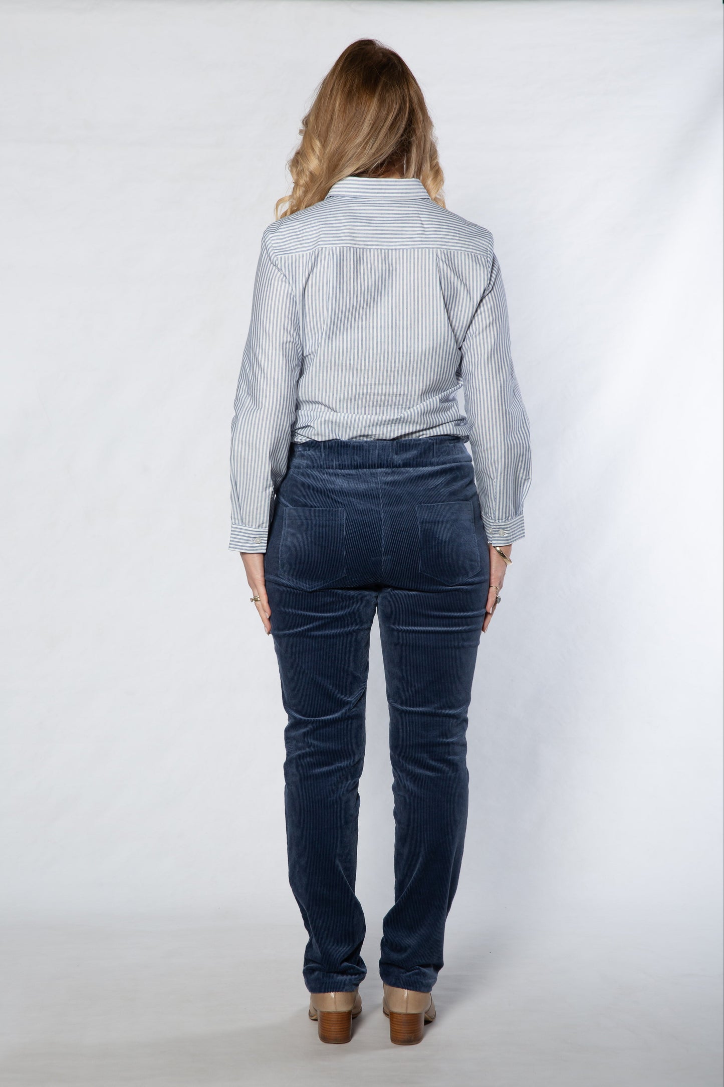 Person wearing a light blue shirt and dark blue jeans on a white background