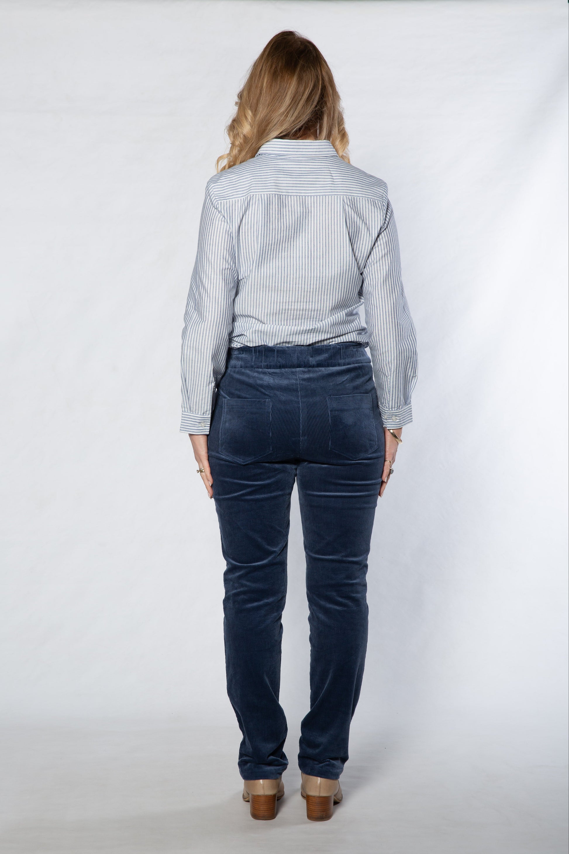 Person wearing a light blue shirt and dark blue jeans on a white background