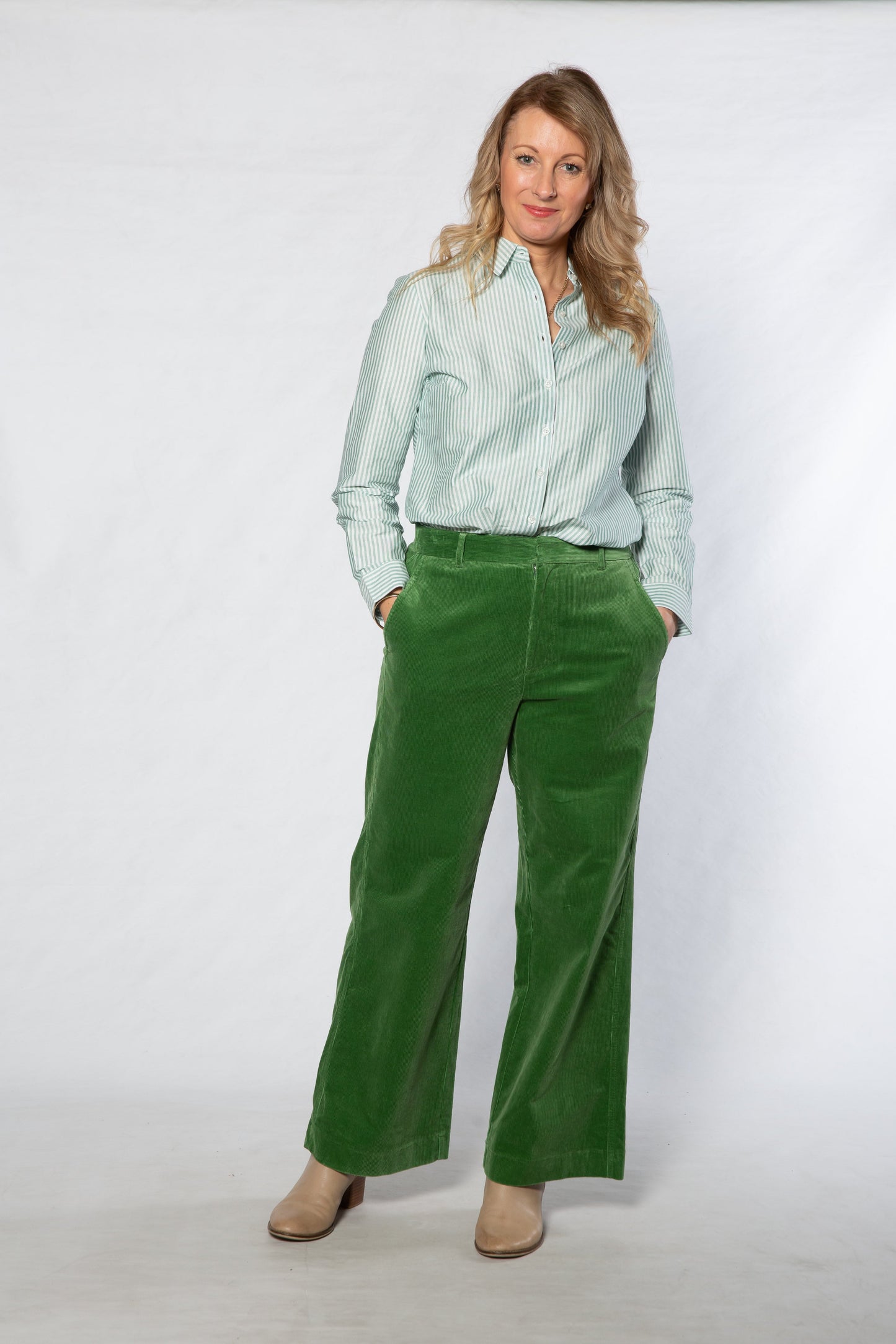 Woman wearing a light green shirt and green pants on a white background