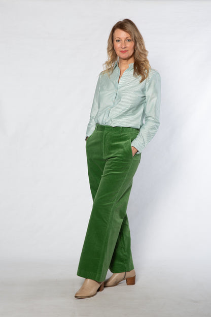 Woman wearing a light green shirt and green pants against a white background
