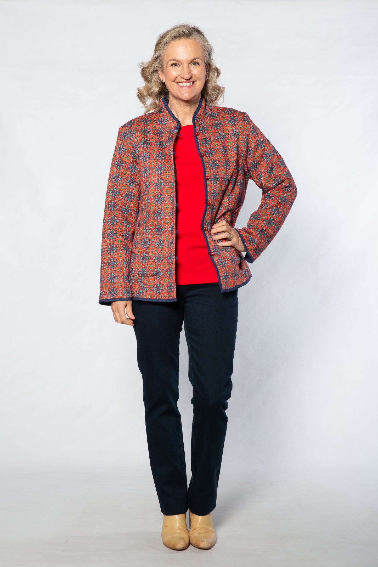 Woman wearing a patterned jacket over a red shirt on a white background