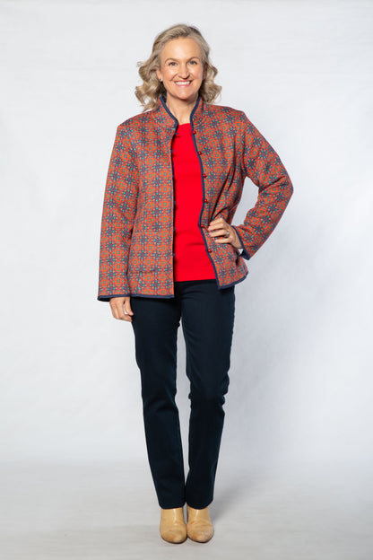 Woman wearing a patterned jacket over a red shirt on a white background