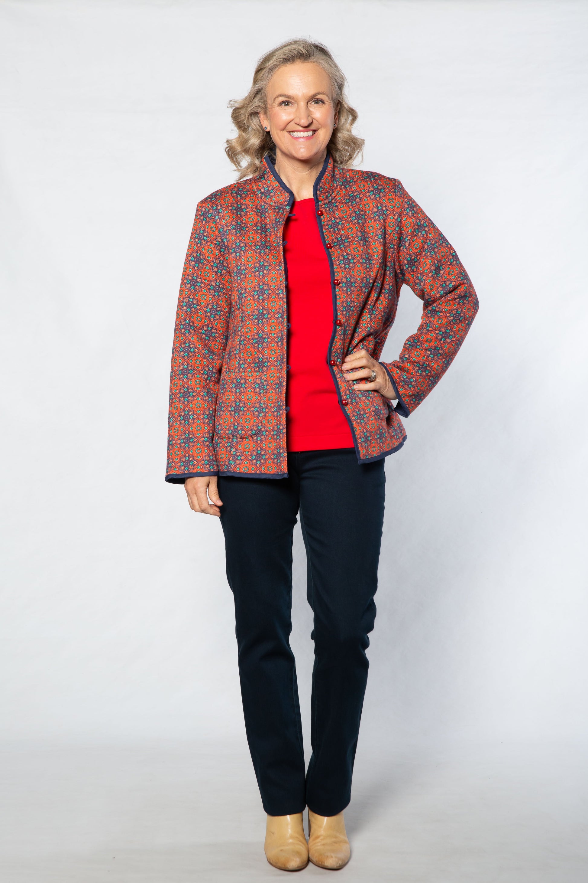 Woman wearing a patterned jacket over a red shirt on a white background